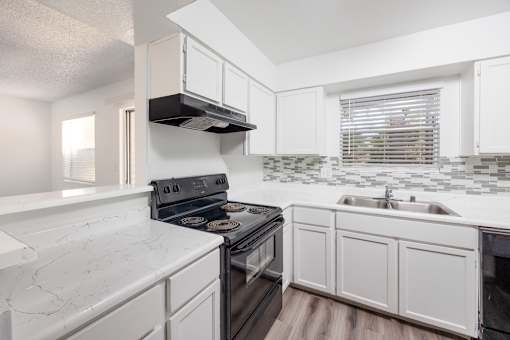 A kitchen with white cabinets and a black stove top oven.