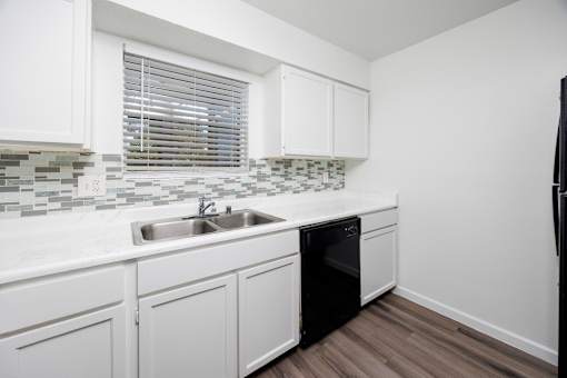A kitchen with white cabinets and a black dishwasher.