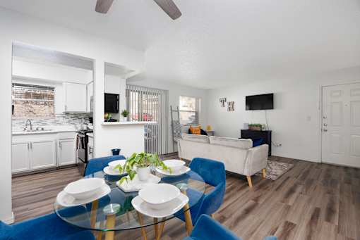 A modern living room with a glass table and blue chairs.