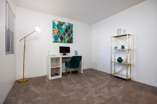 A room with a desk, chair, and a painting on the wall.