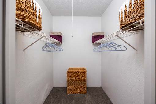 A small closet with two shelves and a basket on the floor.