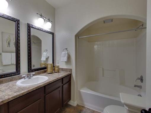 A bathroom with a sink, mirror, toilet and bathtub.