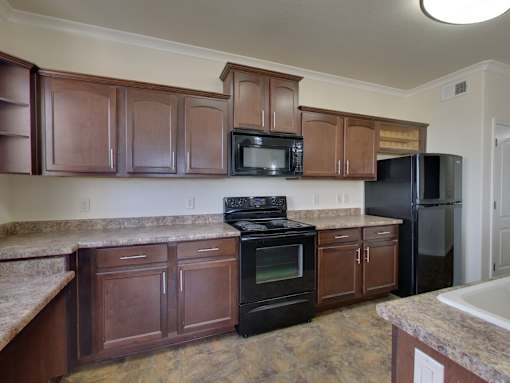 A kitchen with black appliances and brown cabinets.