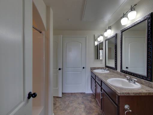 A bathroom with a sink, mirrors and a door.