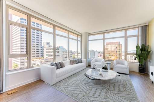 A living room with a large window overlooking a cityscape at The Grand Apartments, Oakland