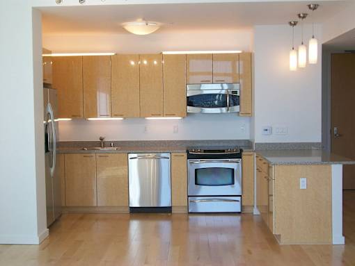 A kitchen with wooden cabinets and stainless steel appliances at The Grand Apartments, Oakland, California