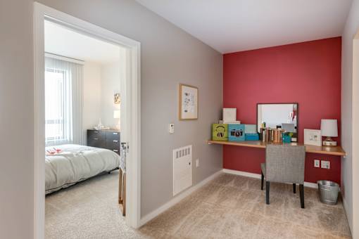 A bedroom with a red wall and a white bed at The Grand Apartments, Oakland, California