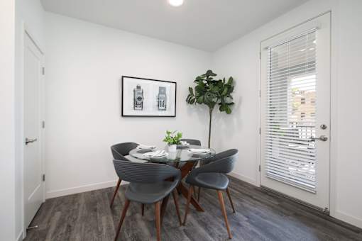 A dining room with a table set for two and a potted plant on the side.