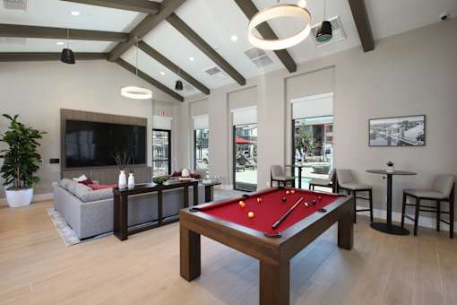 A pool table is in the middle of a room with a couch, chairs, and a television.