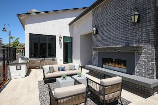 A patio with a fireplace and chairs.