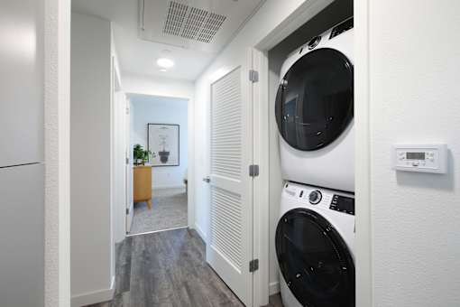A white washing machine is in a small room with a door open.