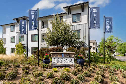The Strand Apartment House is a white building with a garden in front.