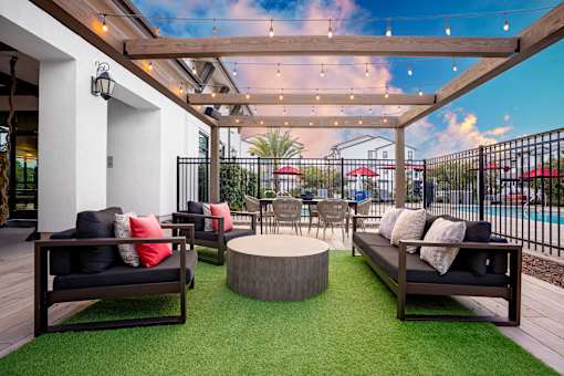 A patio with a black couch and a wooden table.