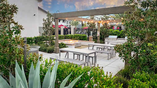 A patio with tables and chairs surrounded by greenery.