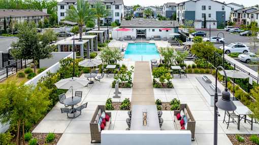 A pool surrounded by a patio with chairs and a table.