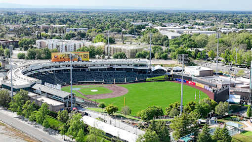 A large stadium with a green field in the center and a yellow sign that says "Catch the Game".