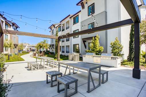 A patio with a table and chairs is surrounded by a white building.