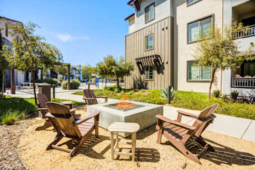 A patio with chairs and a firepit in front of a building.