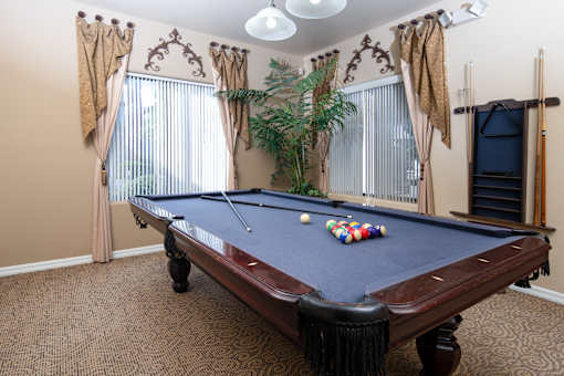 A pool table with a blue cloth and white balls is in the center of the room.