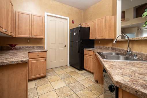 A kitchen with a black refrigerator and wooden cabinets.