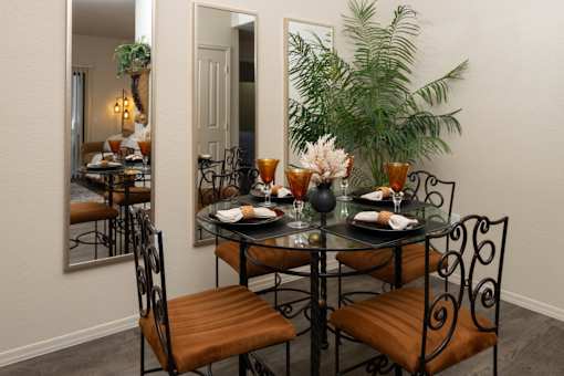 A dining table with chairs and a mirror reflecting a dining room.