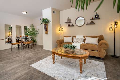 A living room with a couch, coffee table, and potted plants.