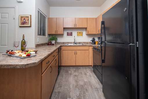 A kitchen with wooden cabinets and a black refrigerator.