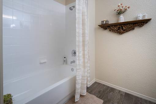 A white bathroom with a white tub and a white shower curtain.