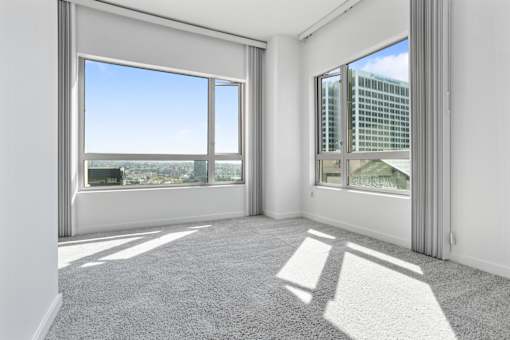 A room with a large window overlooking a cityscape at The Grand Apartments, California, 94612