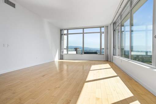 A room with wooden flooring and large windows overlooking a cityscape at The Grand Apartments, Oakland