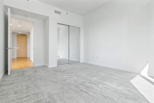 A white room with a carpeted floor and a sliding glass door at The Grand Apartments, Oakland, California