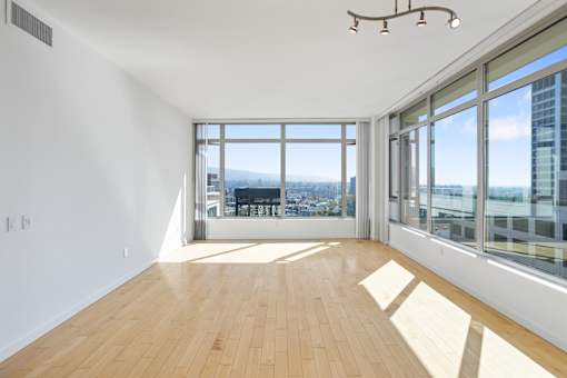 A room with wooden floors and large windows overlooking a cityscape at The Grand Apartments, Oakland 94612