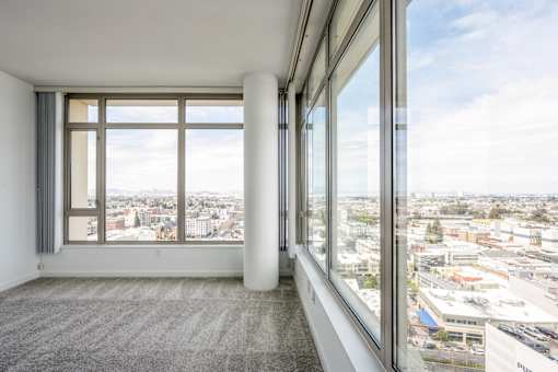 A room with a large window overlooking a cityscape at The Grand Apartments, Oakland