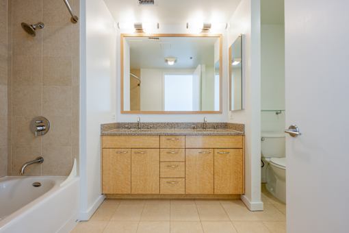 A bathroom with a tub, sink, and mirror at The Grand Apartments, Oakland, CA, 94612