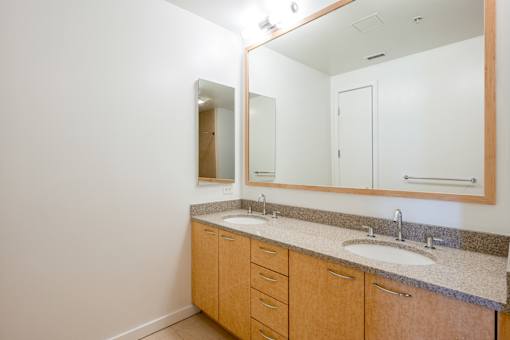 A bathroom with a sink, mirror, and cabinets at The Grand Apartments, California, 94612