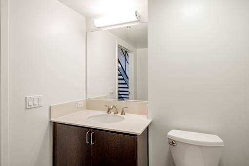 A bathroom with a sink, toilet and mirror at The Grand Apartments, Oakland