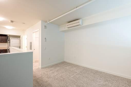 A room with a carpeted floor and a wall-mounted air conditioner at The Grand Apartments, Oakland, CA
