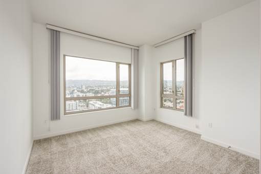 A large, empty room with a view of the city through the windows at The Grand Apartments, Oakland 94612