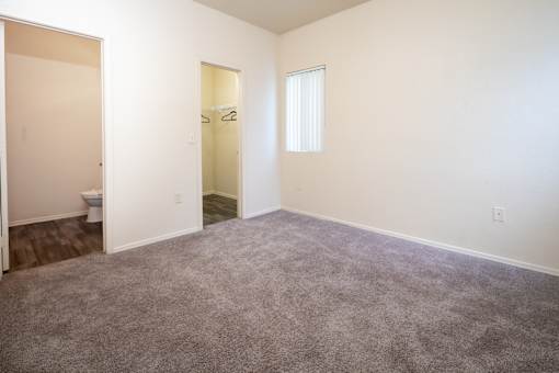 A room with a carpeted floor and a window with blinds.