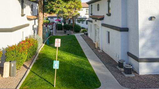 A sign on a post in a grassy area between two buildings.