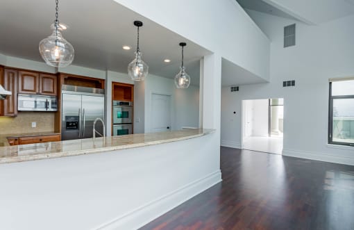 an open kitchen and living room with white walls and wood floors at Vendome Place, San Jose