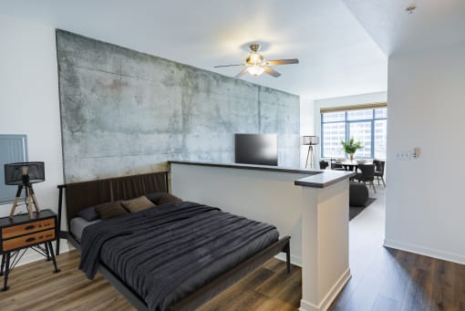 a bedroom with a bed and a wall with a concrete wall behind it at Vendome Place, San Jose, 95110