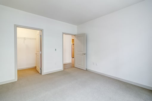 the living room and bedroom of an apartment with white walls and carpet
