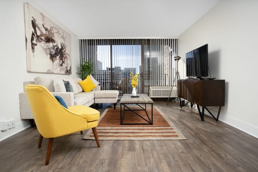 Livingtoom with yellow chair, flat screen TV , enterainment center, coffee table  and rug at Vera Cortez Hill, San Diego, 92101