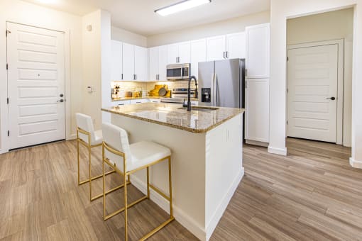 a kitchen with white cabinets and a granite counter top at Waterford RiNo, Denver, CO