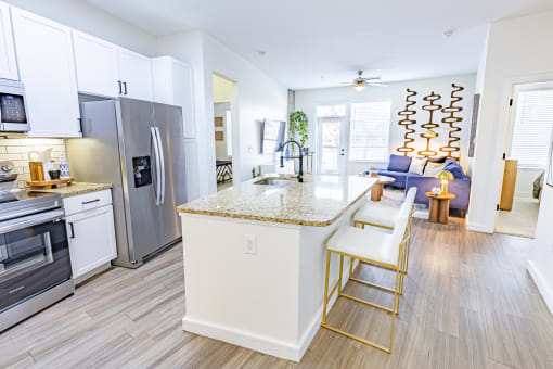 a kitchen with stainless steel appliances and an island with two stools at Waterford RiNo, Colorado 80216