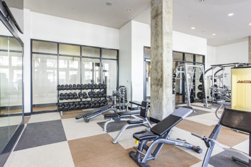 a gym with weights and cardio equipment on the floor and windows at Waterford RiNo, Denver, 80216