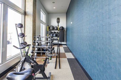 a workout room with weights and a blue wall and a window at Waterford RiNo, Denver, Colorado