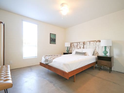 Dog-Friendly Apartments In Old Town Scottsdale - Spacious Bedroom With Light Fixture, A Window, And Concrete-Style Flooring.