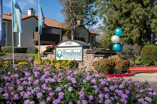 Property entrance sign with colorful landscaping at Woodbend Apartments, Alta Loma, California